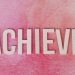 The word 'Achieve' in wooden letters on a textured pink background, symbolizing success and motivation.